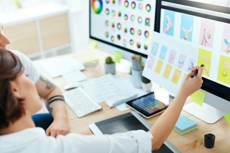 A designer reviewing colour studies and layouts on a large screen