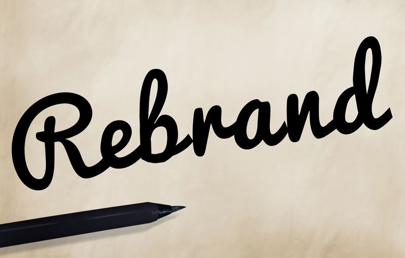 The word Rebrand handwritten in black brush script on paper